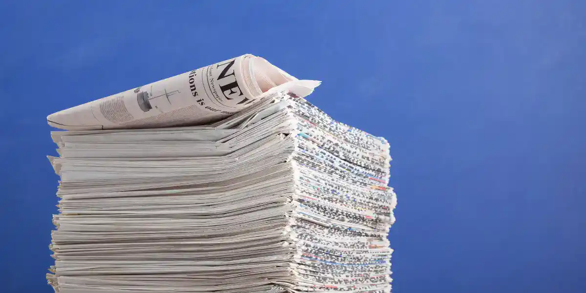 Stack of newspapers and documents representing medical technology updates and clinical evidence reports.